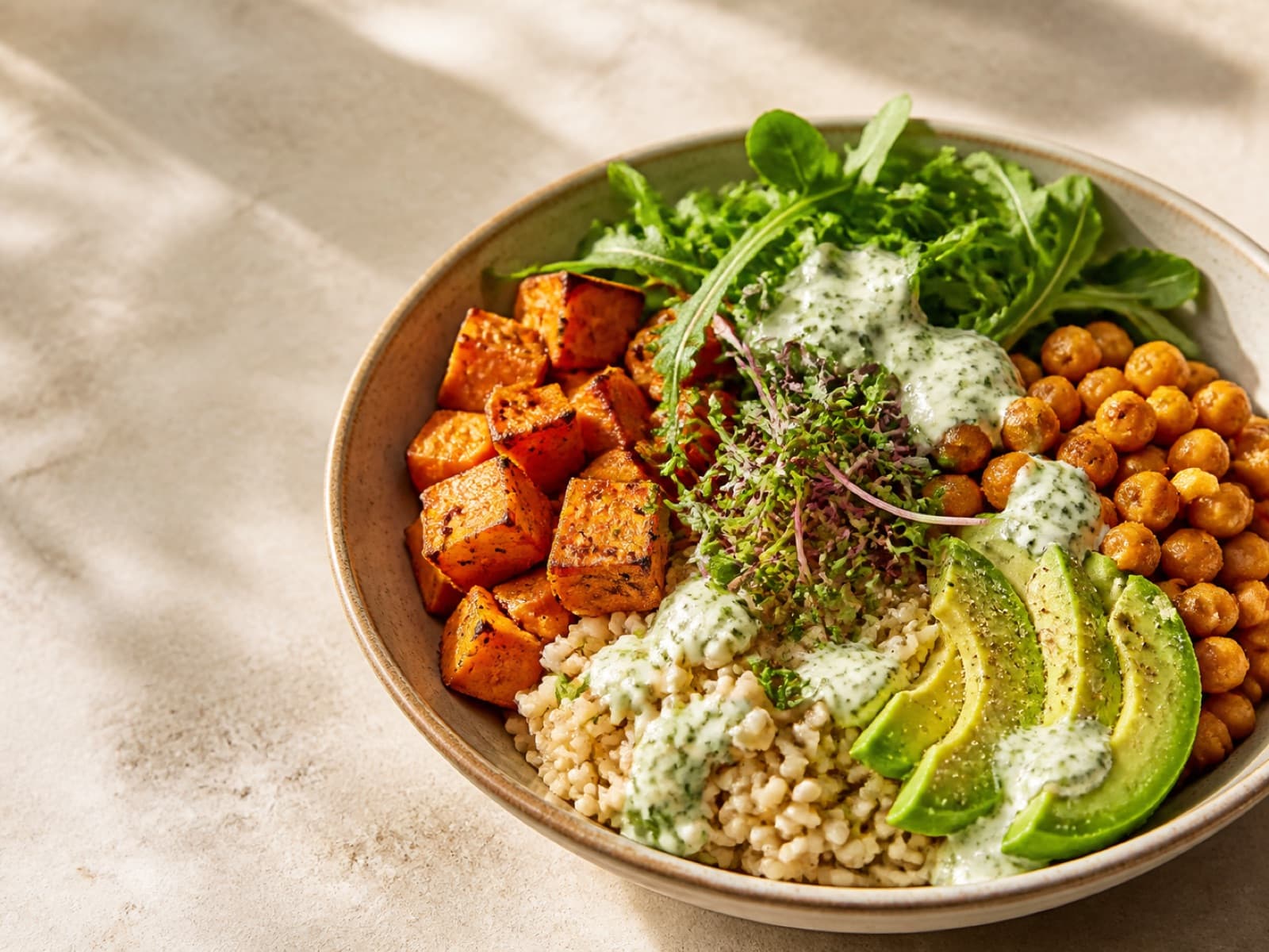 A colourful healthy dinner bowl with sweet potato, chickpeas, avocado, and greens