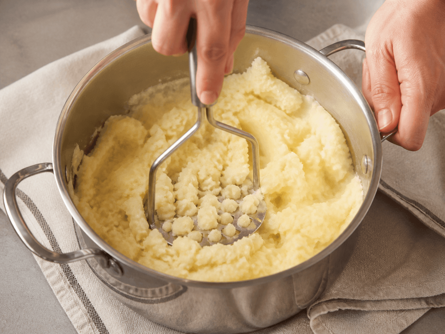 Mashing boiled potatoes to make homemade mashed potatoes